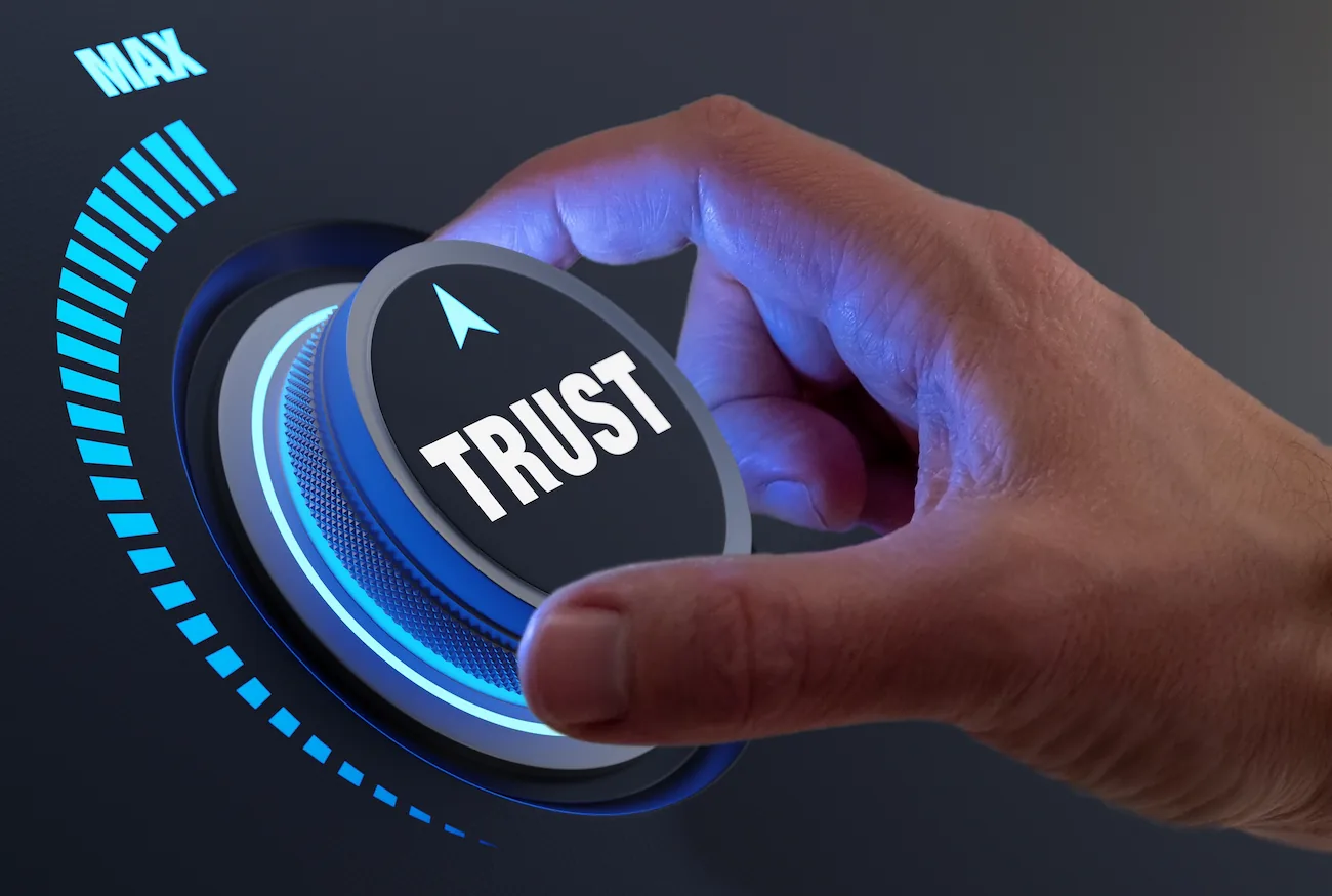 Hand turning up a control knob with the word 'Trust' on top of it